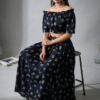 Side view of women black floral off shoulder co-ord set with long skirt